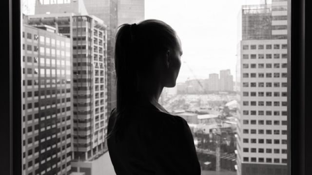 Stock image of woman looking out an office window.