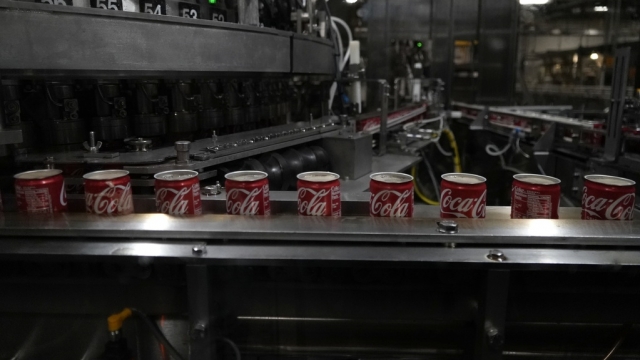 Coca-Cola cans move down a conveyer belt.