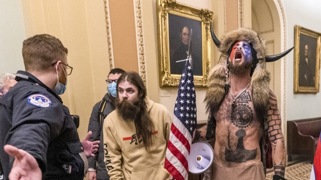 Jacob Chansley, wearing a fur hat with horns, is confronted by U.S. Capitol Police officers outside the Senate Chamber.