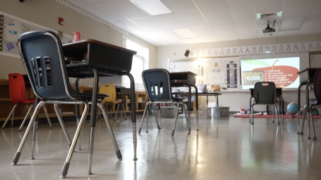 A classroom sits empty with the lights dim.