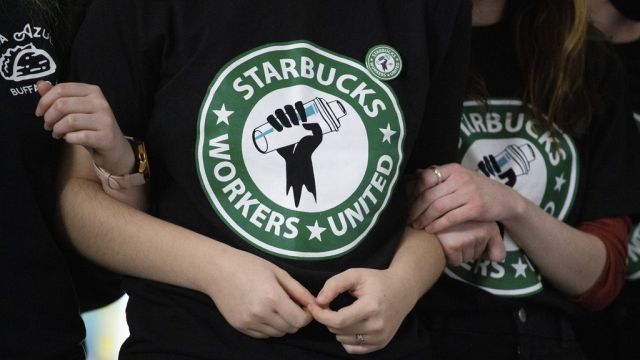 Starbucks employees and supporters link arms during a union election watch party.