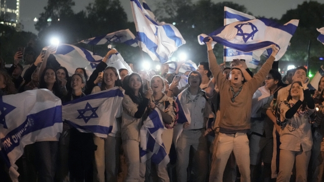 A group of Israelis celebrate as a helicopter carrying hostages released from the Gaza Strip lands on a hospital helipad