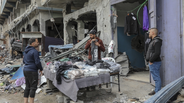 Palestinians sell clothes in front of their destroyed store on the main road in Beit Lahiya, Gaza Strip