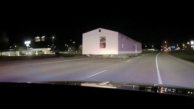 Police dash cam footage shows officers pursuing a car that's towing a mobile home.