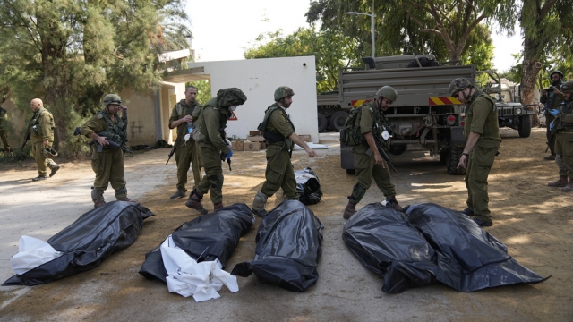 Israeli soldiers stand next to the bodies of Israelis killed by Hamas militants in kibbutz Kfar Azza.