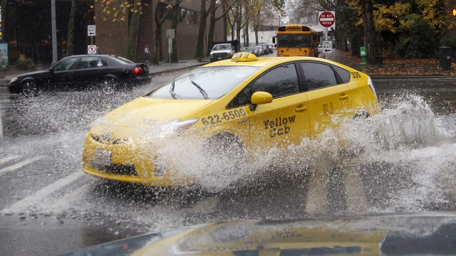 A taxi sends up a wave of water while driving