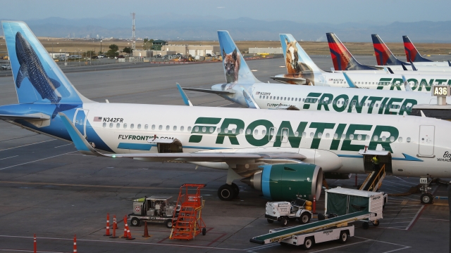 Frontier Airlines jets sit at gates at Denver International Airport.