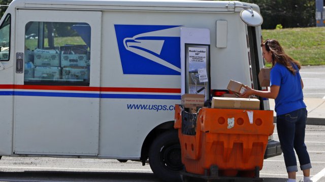 File photo of a postal worker loading a delivery vehicle.