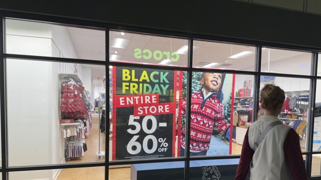 Shoppers passes by window sign for Black Friday sales.