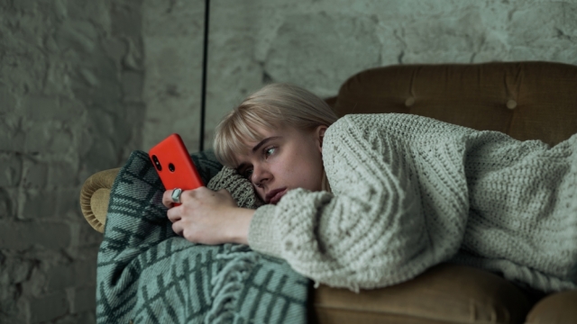 Woman lying on a couch looking at her phone