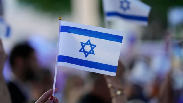 Person waves a small Israeli flag.