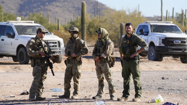 Members of the U.S. Border Patrol and U.S. Customs and Border Protection stand at the Arizona border.
