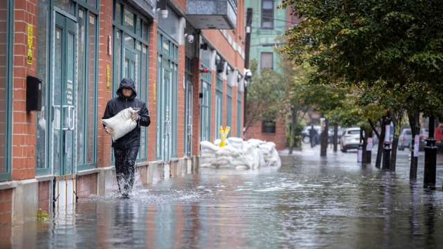 A person carries a sand bag during a flood