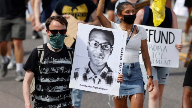 A demonstrator carries an image of Elijah McClain during a rally and march