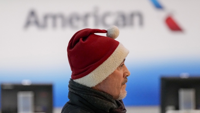 A man with a Santa hat stands near an American desk.