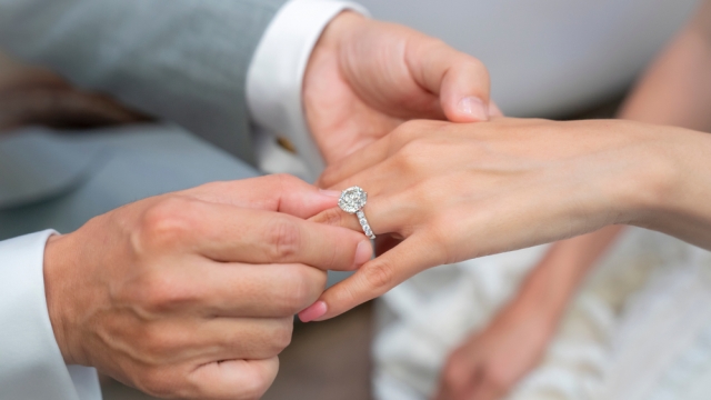 A man puts an engagement ring on a woman's hand.