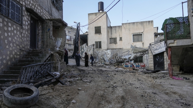 Palestinians walk through the aftermath of the Israeli military raid on Nur Shams refugee camp in the West Bank.