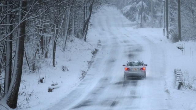 A car treks down a snow covered road, Sunday, Jan. 7, 2024, in Derry, New Hampshire.