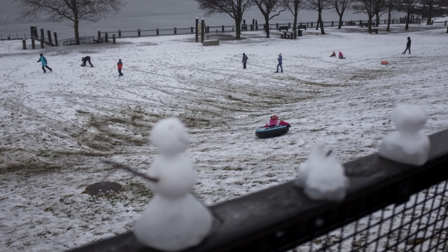 Miniature snowmen melt on a railing as children play in park, Sunday, Jan. 7, 2024, in Providence, R.I.