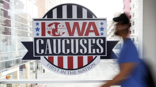 Pedestrian walks past a sign for the Iowa Caucuses.