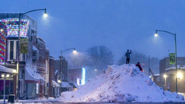 People stand on an large snow pile in Oskaloosa, Iowa