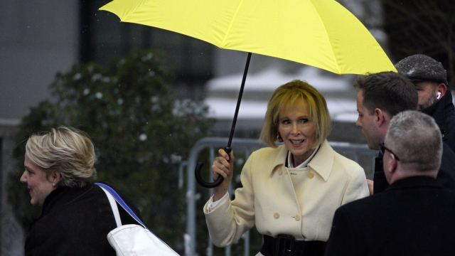 E. Jean Carroll holds a yellow umbrella outside of court