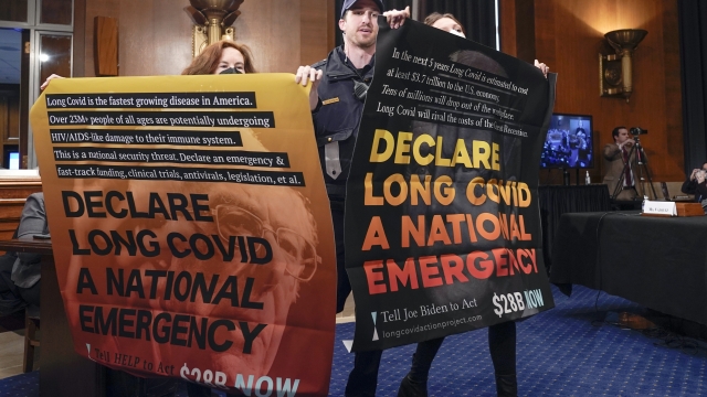 People protest during a Senate Health, Education, Labor, and Pensions hearing to examine addressing long COVID