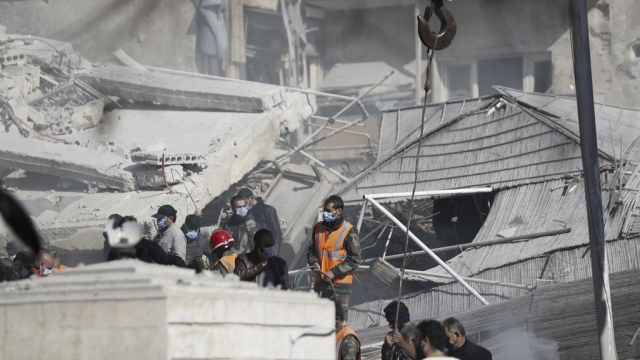 Emergency services work at a building hit by an air strike in Damascus, Syria, Saturday, Jan. 20, 2024.