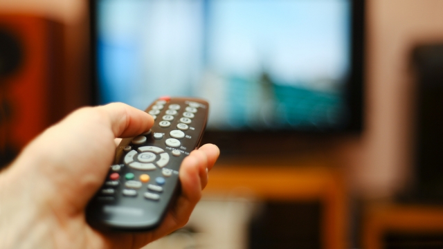 Person pointing a remote at a television.