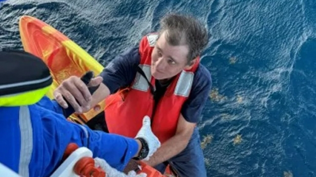 A Carnival cruise crew member pulls a man stranded at sea aboard.