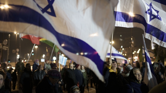 People holding up Israeli flags take part in a protest against humanitarian aid entering Gaza.