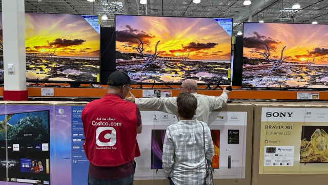 Customers consider big-screen televisions in a Costco warehouse.
