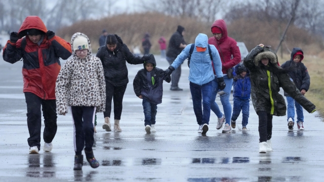 Migrants run in the rain toward a migrant housing location in New York.