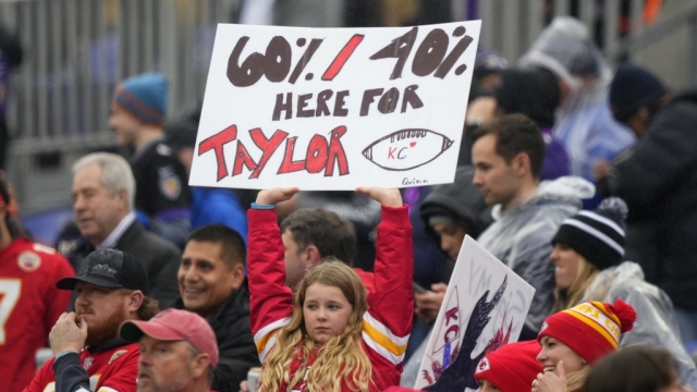 A girl holds a sign for Taylor Swift at an NFL football game.