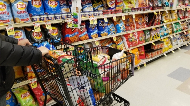 A person pushes a grocery cart through the chips aisle.