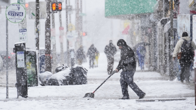 A person clears off a sidewalk during a winter snow storm in Philadelphia.