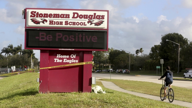 In this Feb. 23, 2019, photo, a bicyclist rides past a sign at Marjory Stoneman Douglas High School in Parkland, Fla