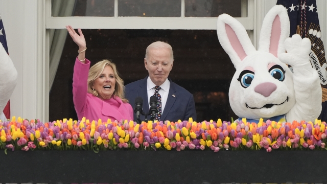 President Joe Biden and first lady Jill Biden wave from the Blue Room Balcony toward the White House Easter Egg Roll.
