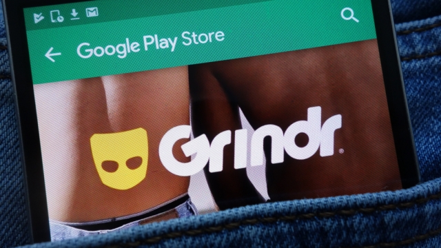 Grindr app on Google Play Store website displayed on smartphone in jeans pocket