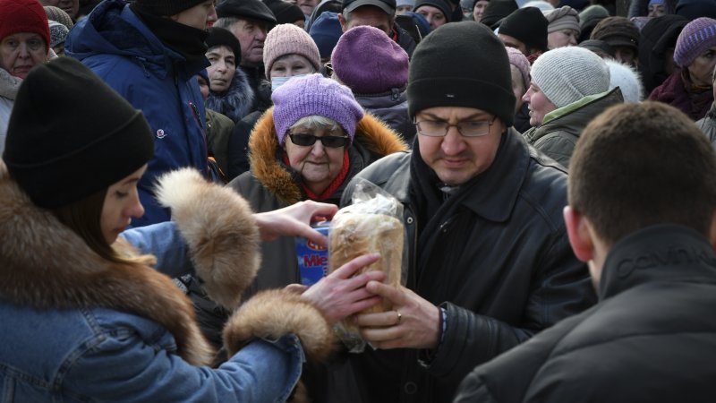 People receive bread at a humanitarian aid distribution spot