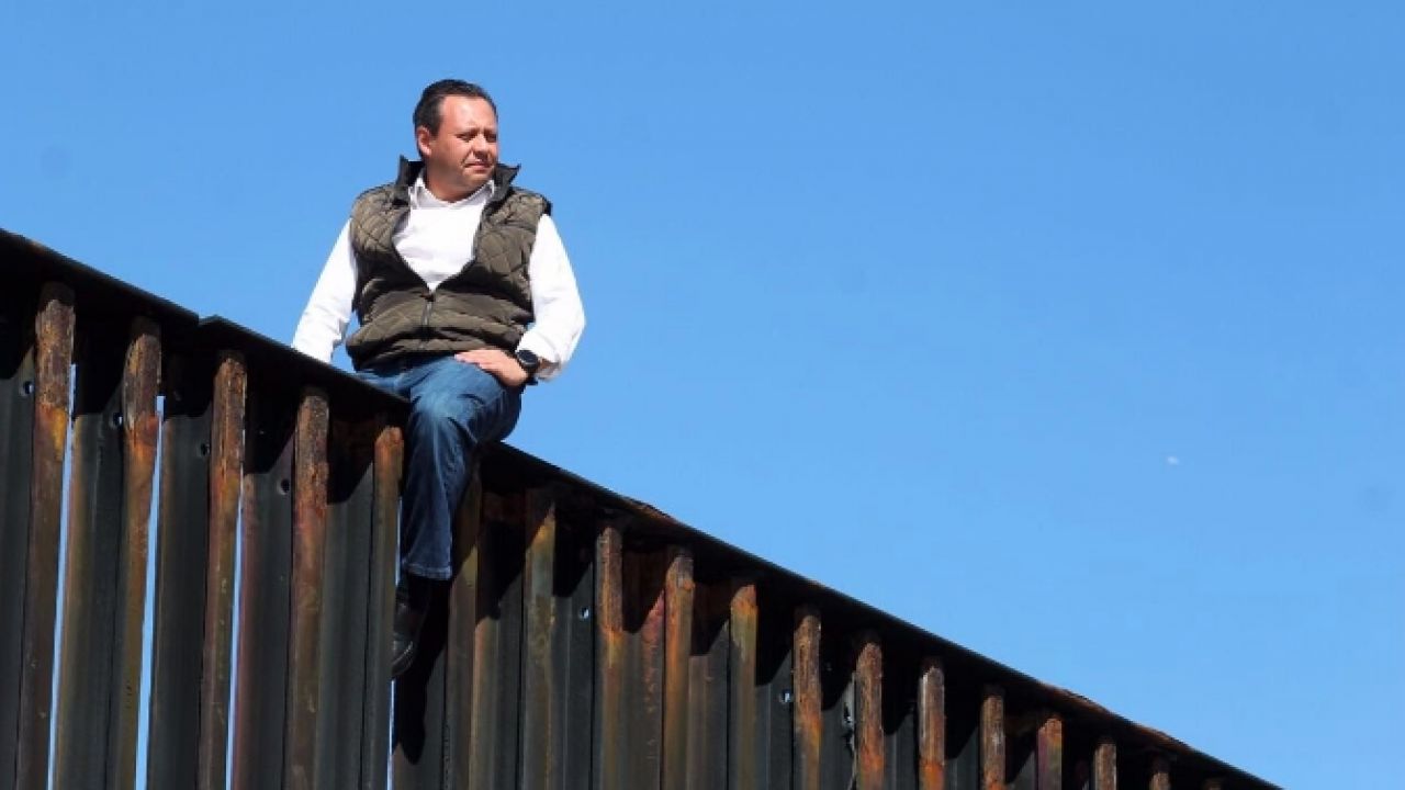 Braulio Guerra sits atop the border fence between US and Tijuana