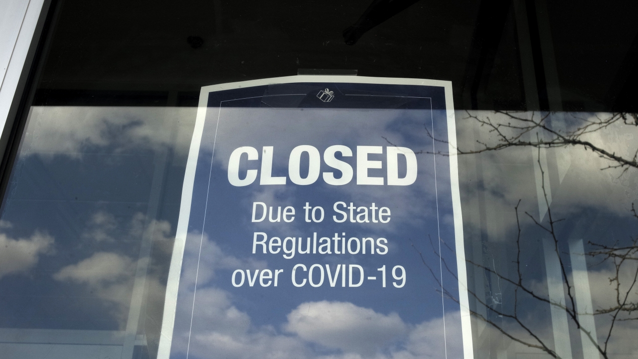 A closed sign is posted in the window of a store because of COVID-19