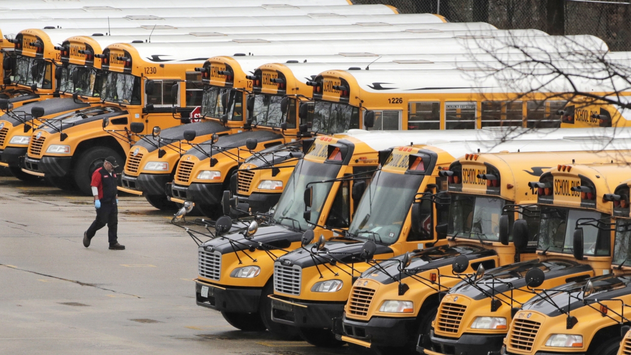 A worker passes public school buses parked at a depot in Manchester, New Hampshire