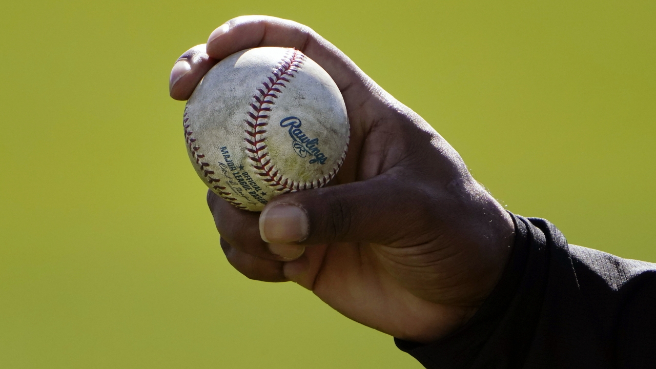 An MLB pitcher shows his grip on a baseball.