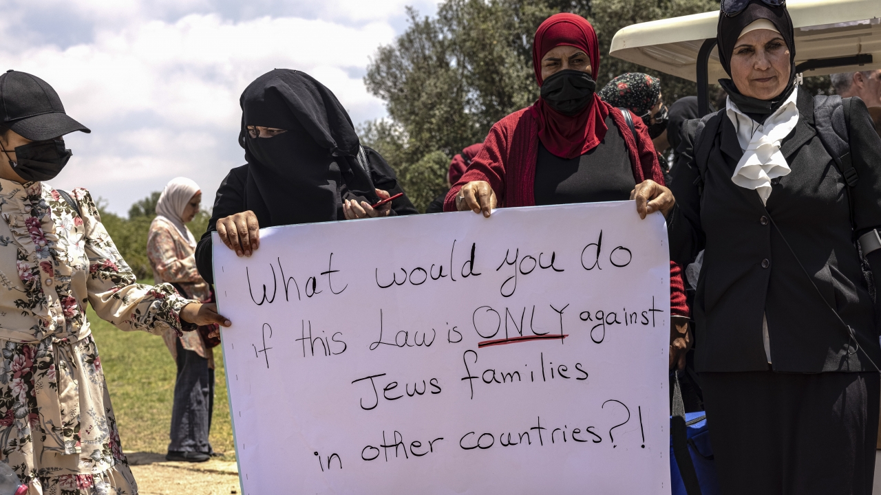 Israeli Arab women hold a sign during a protest ahead of a vote by Israel's parliament.