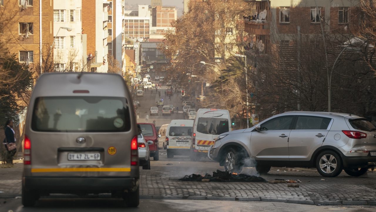 Cars drive around a burning tire on the street in Hillbrow, Johannesburg, South Africa
