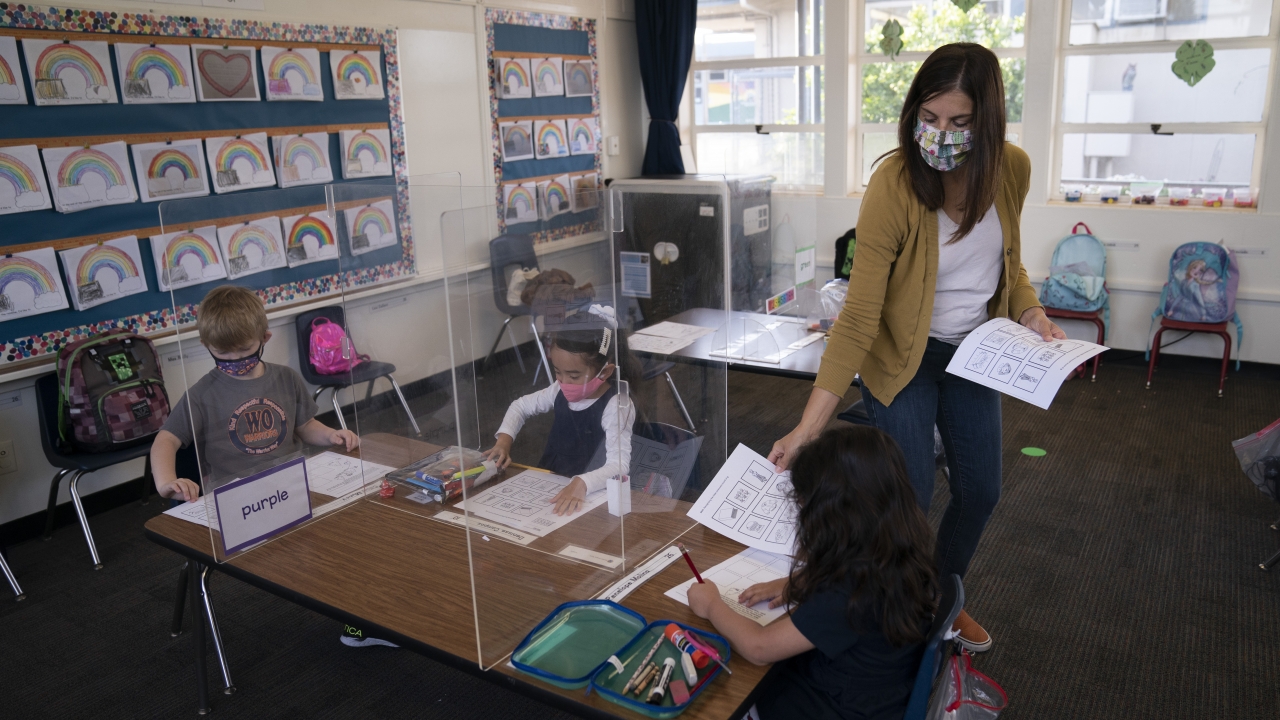 Kindergarten teacher hands printouts to her students at West Orange Elementary School in Orange, California