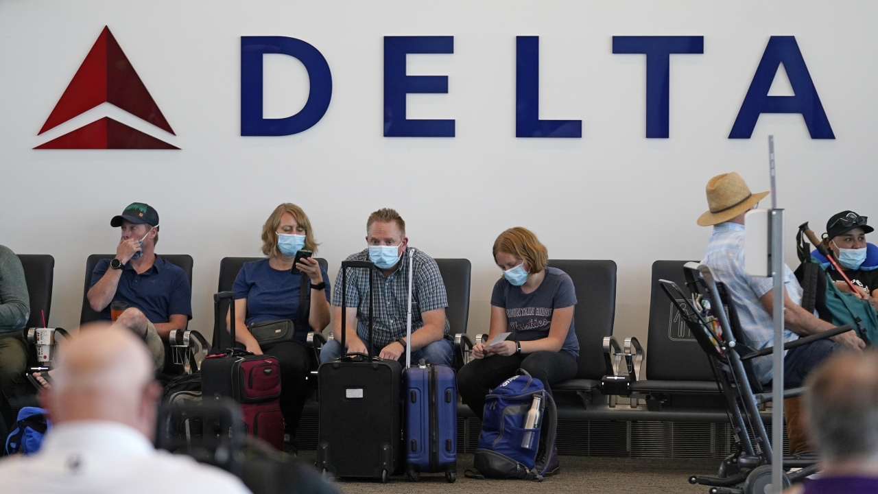 People sit under Delta sign at Salt Lake City International Airport.