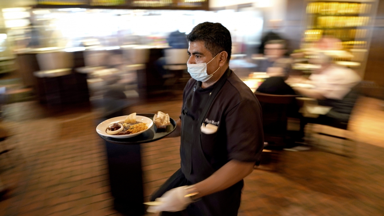 Marcelino Flores wears a face mask as he delivers food to a table at Picos restaurant in Houston in March 2021.