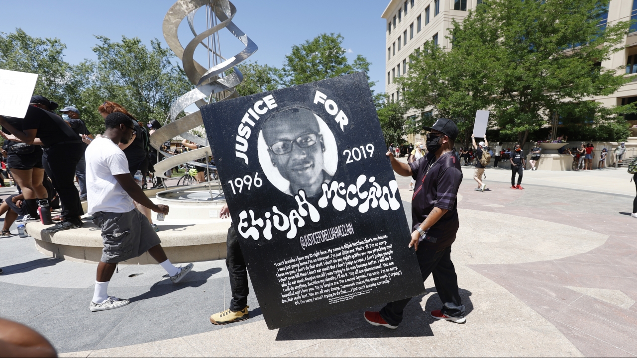 demonstrators carry a giant placard during a rally and march over the death of Elijah McClain